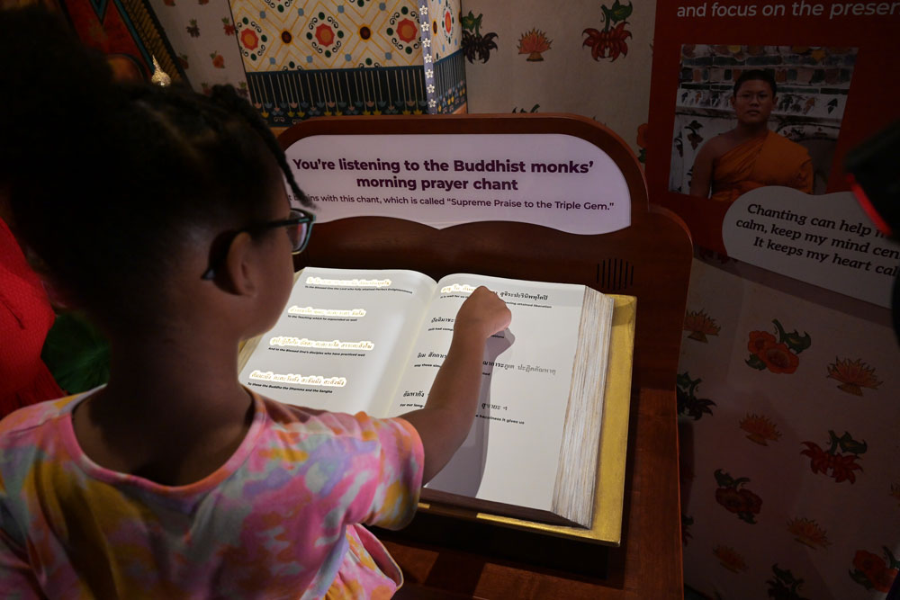 Child pointing at chant book with words highlighted.